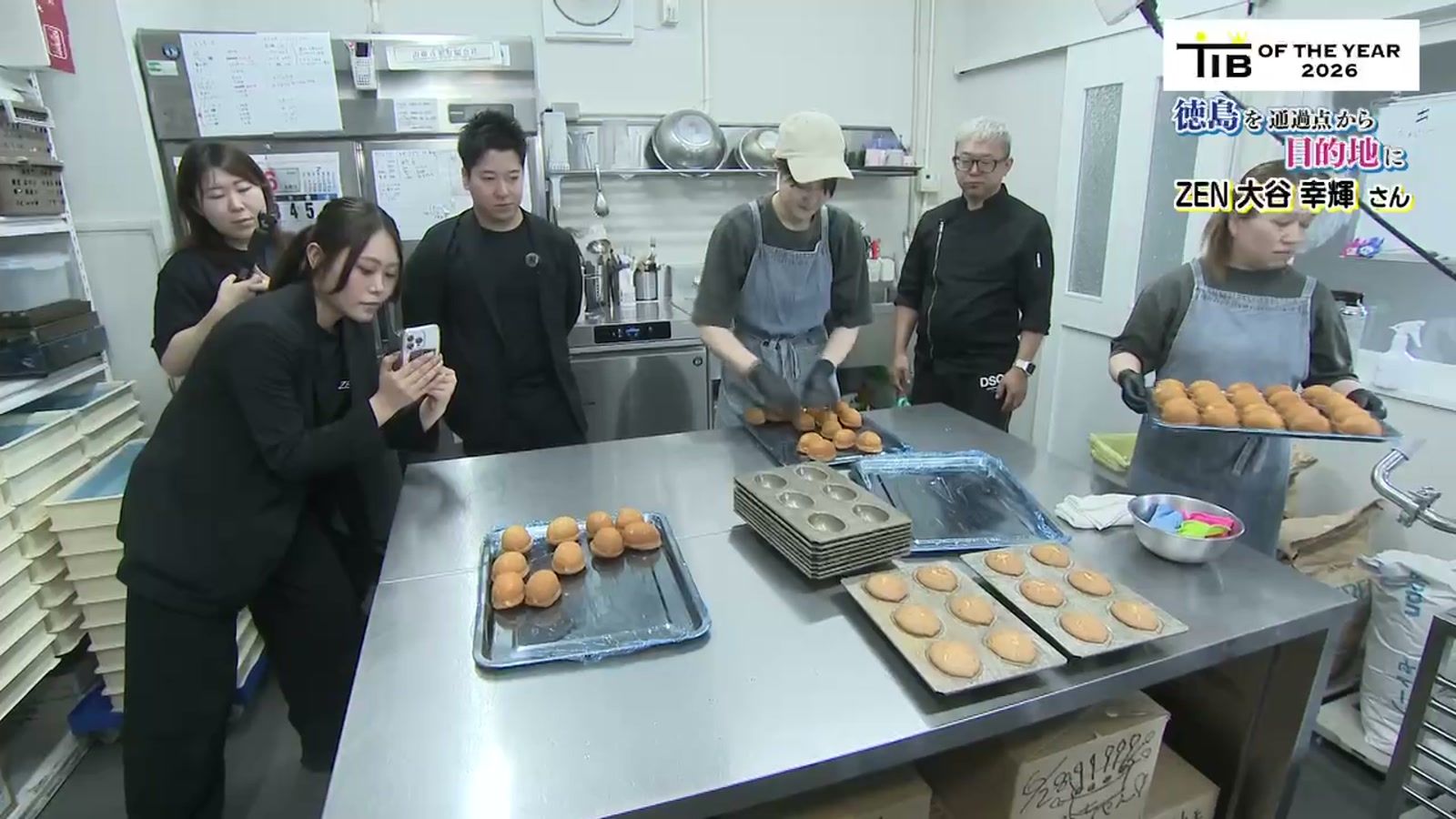 洋菓子店の厨房で、お店のスタッフと撮影を進めるZENのメンバー