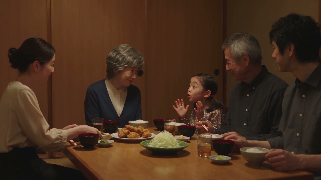三世代の家族が同じ食卓を囲み、笑顔で食事を楽しむ